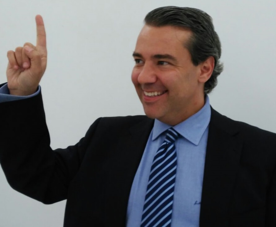 Juan Pablo sonriendo y señalando hacia arriba con un dedo.