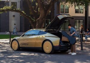 Vehículo Cybercab dorado con el portón trasero abierto y una persona junto a él
