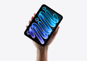 Una mano sostiene una tableta negra con una pantalla de formas luminosas azules y violetas.